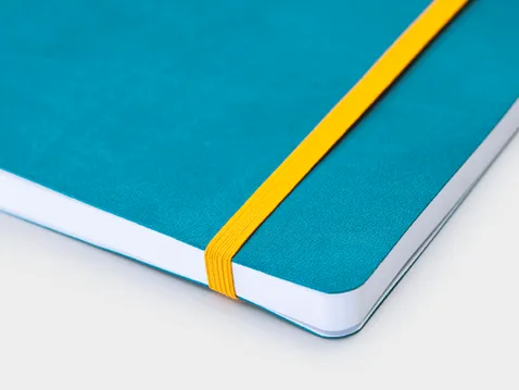 Close-up of a turquoise A5 diary soft cover with logo and yellow elastic band